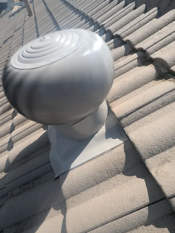 Silver whirlybird turbine vent installed on a tiled roof